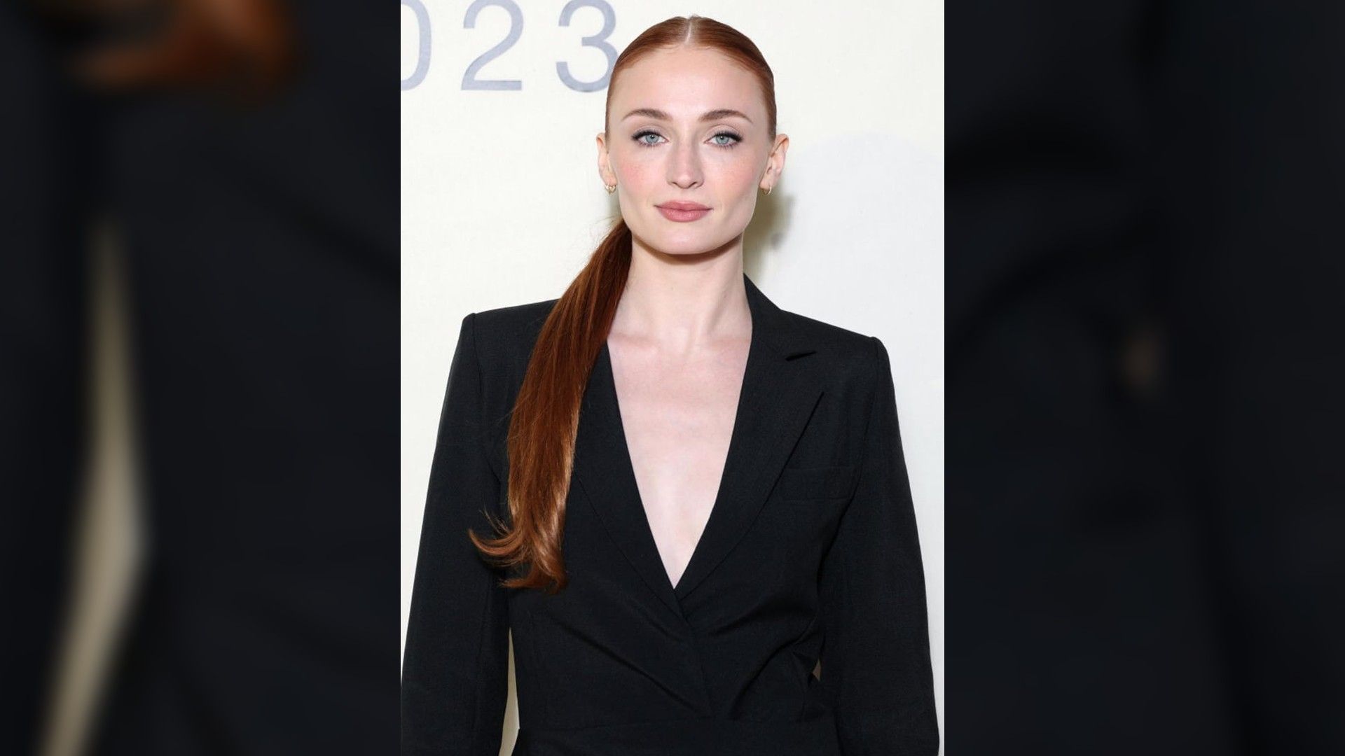 Actrița Sophie Turner fotografiată de la brâu în sus. Părul prins într-o coadă de cal și un sacou