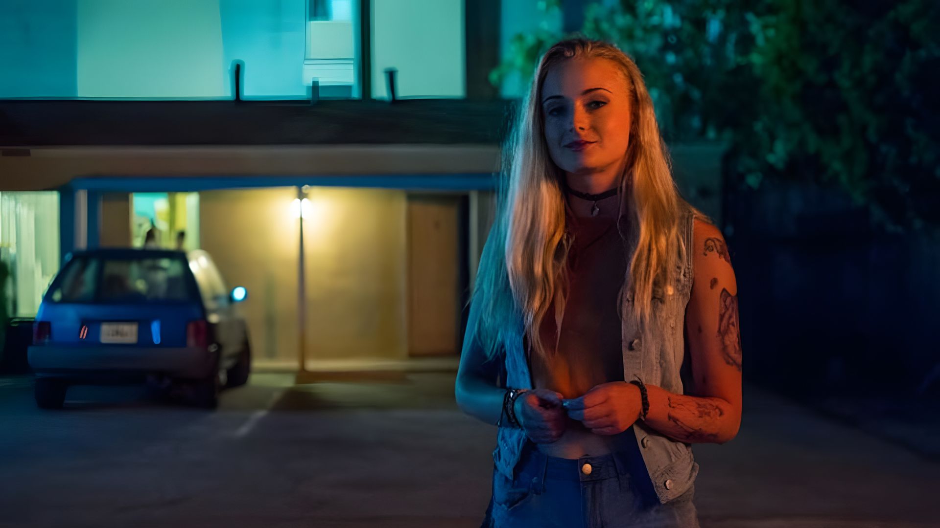 Sophie Turner poartă pantaloni scurți și o vestă de denim, având un tatuaj pe brațul stâng