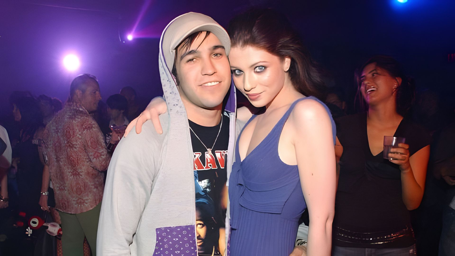 Actrița Michelle Trachtenberg și muzicianul Pete Wentz se îmbrățișează în timp ce oamenii se distrează în fundal