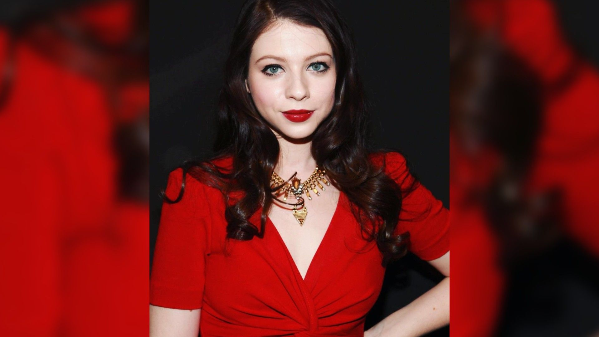 Actrița Michelle Trachtenberg într-o rochie roșie și machiaj strălucitor cu ruj roșu care se potrivește cu culoarea rochiei