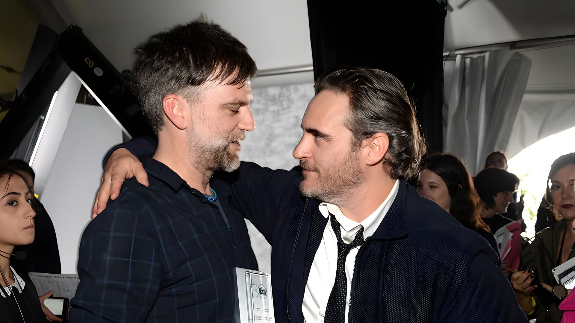 Joaquin Phoenix îl îmbrățișează pe Paul Thomas Anderson cu o mână