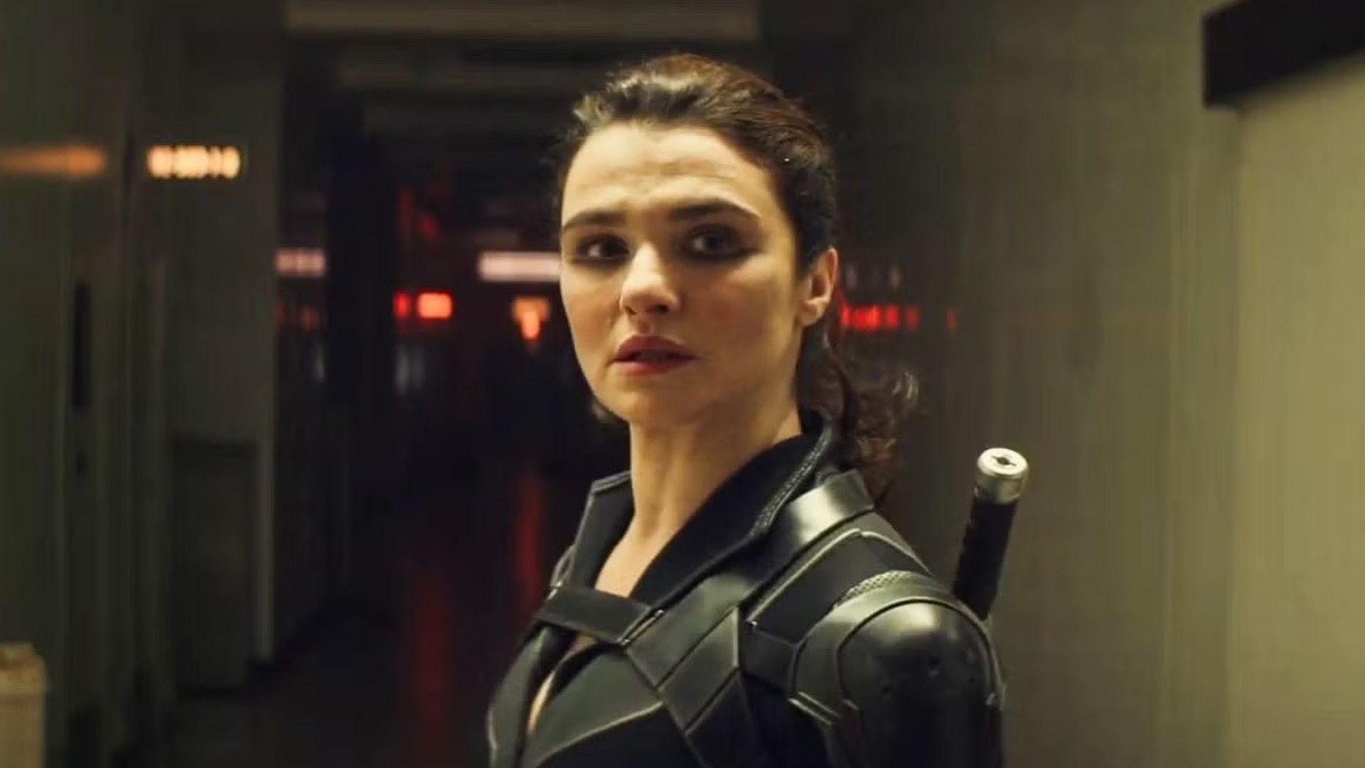 Actrița Rachel Weisz cu părul prins în coadă de cal, purtând un costum negru de supererou