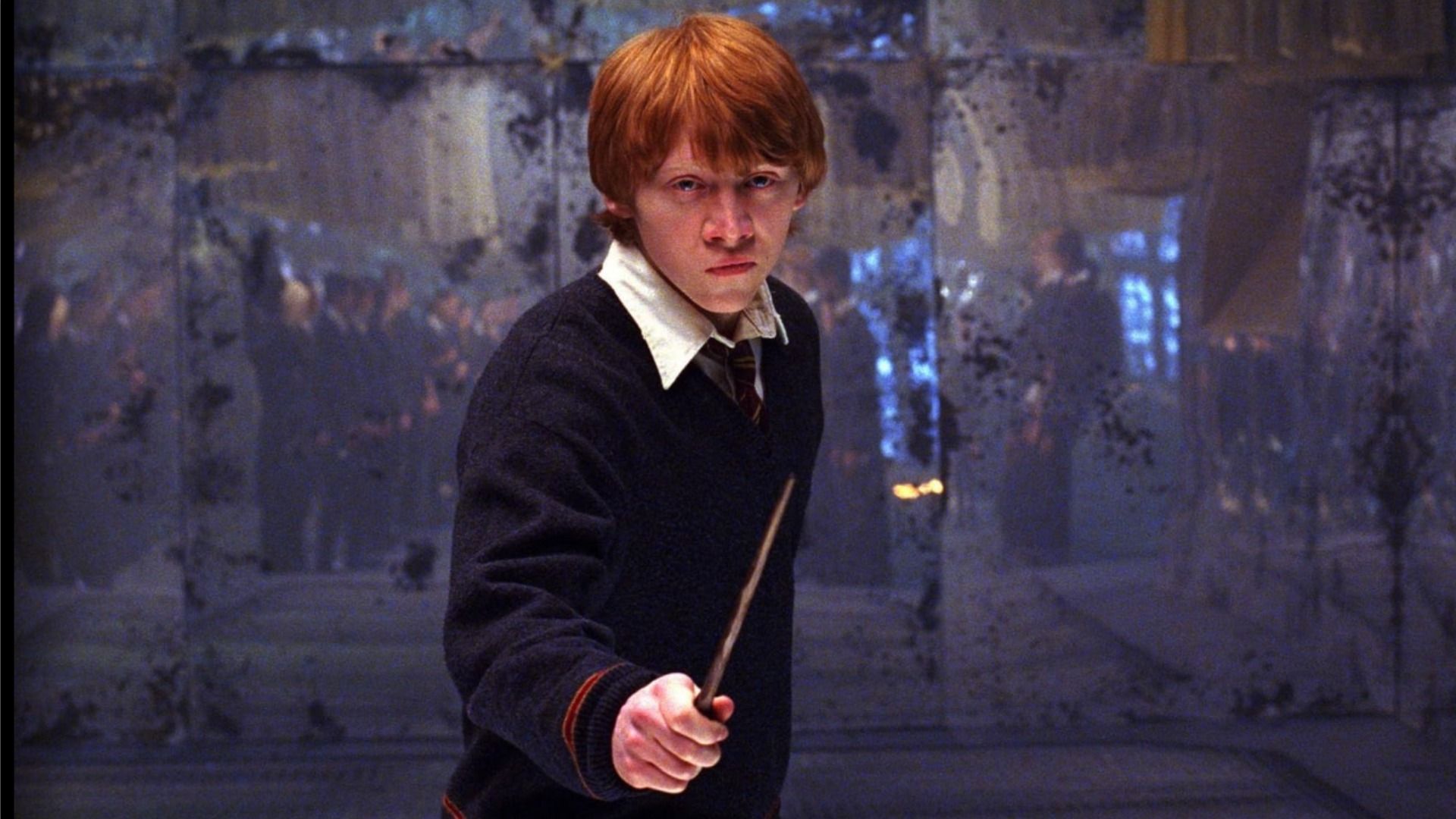 Actorul Rupert Grint în tinerețe ca Ron Weasley, stând cu o baghetă în fața unei oglinzi