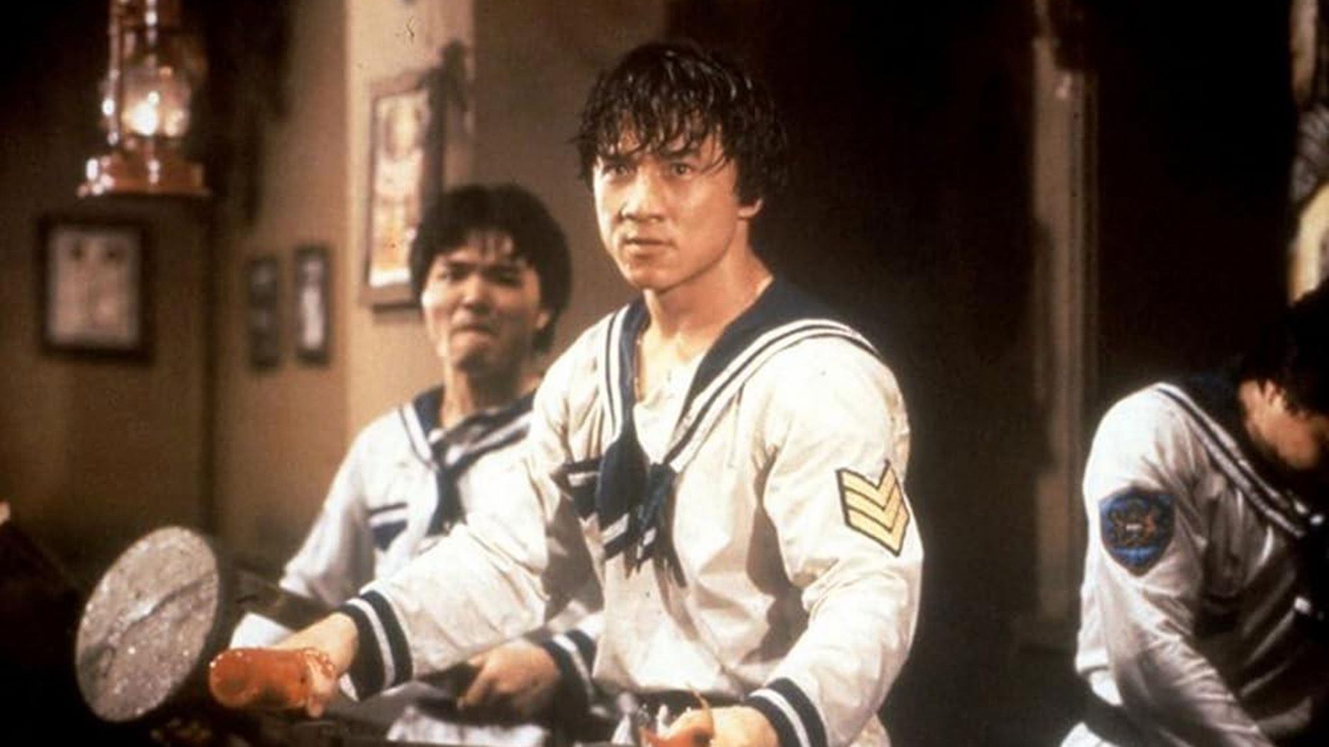 Tânărul Jackie Chan în costum de marinar pregătit pentru luptă într-o scenă din 'Project A'