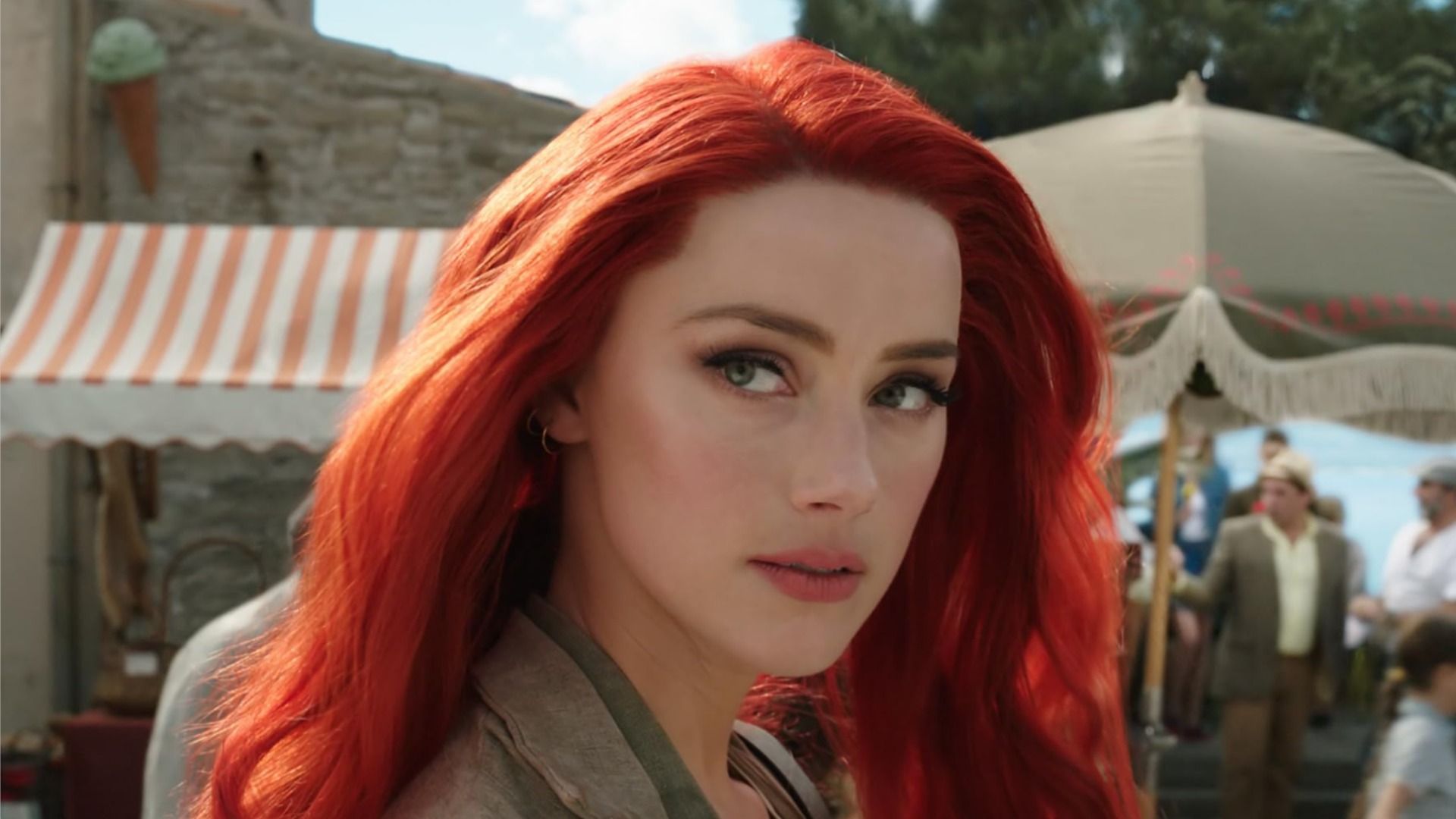 Actrița Amber Heard cu părul roșu privește lateral pe fundalul străzii și al oamenilor