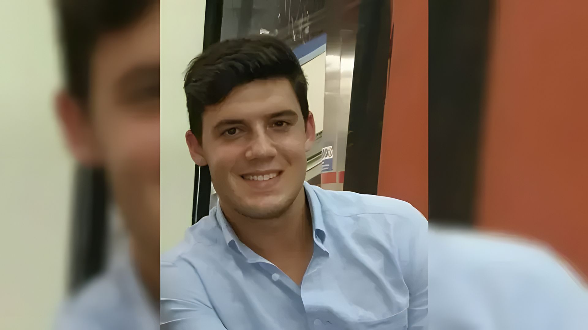 Un tânăr zâmbește la cameră, fundalul este estompat