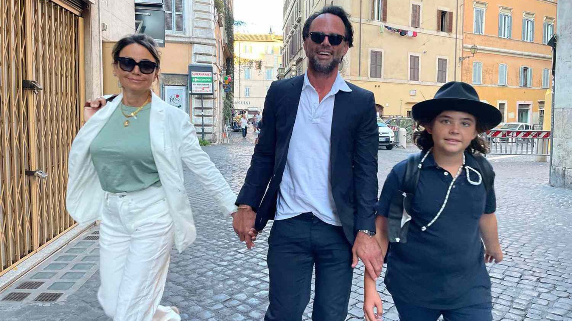 Walton Goggins, soția sa Nadia Conners și fiul lor Augustus merg pe stradă și zâmbesc