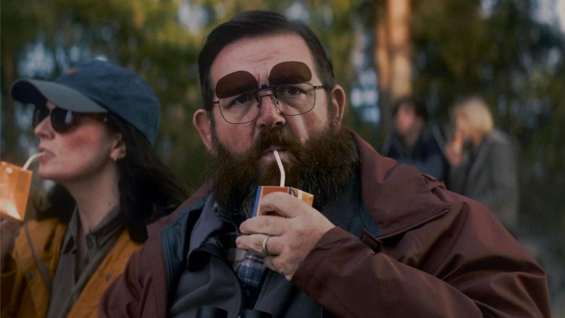 Actorul Nick Frost cu ochelari bea suc dintr-o cutie de carton printr-un pai și privește la cameră
