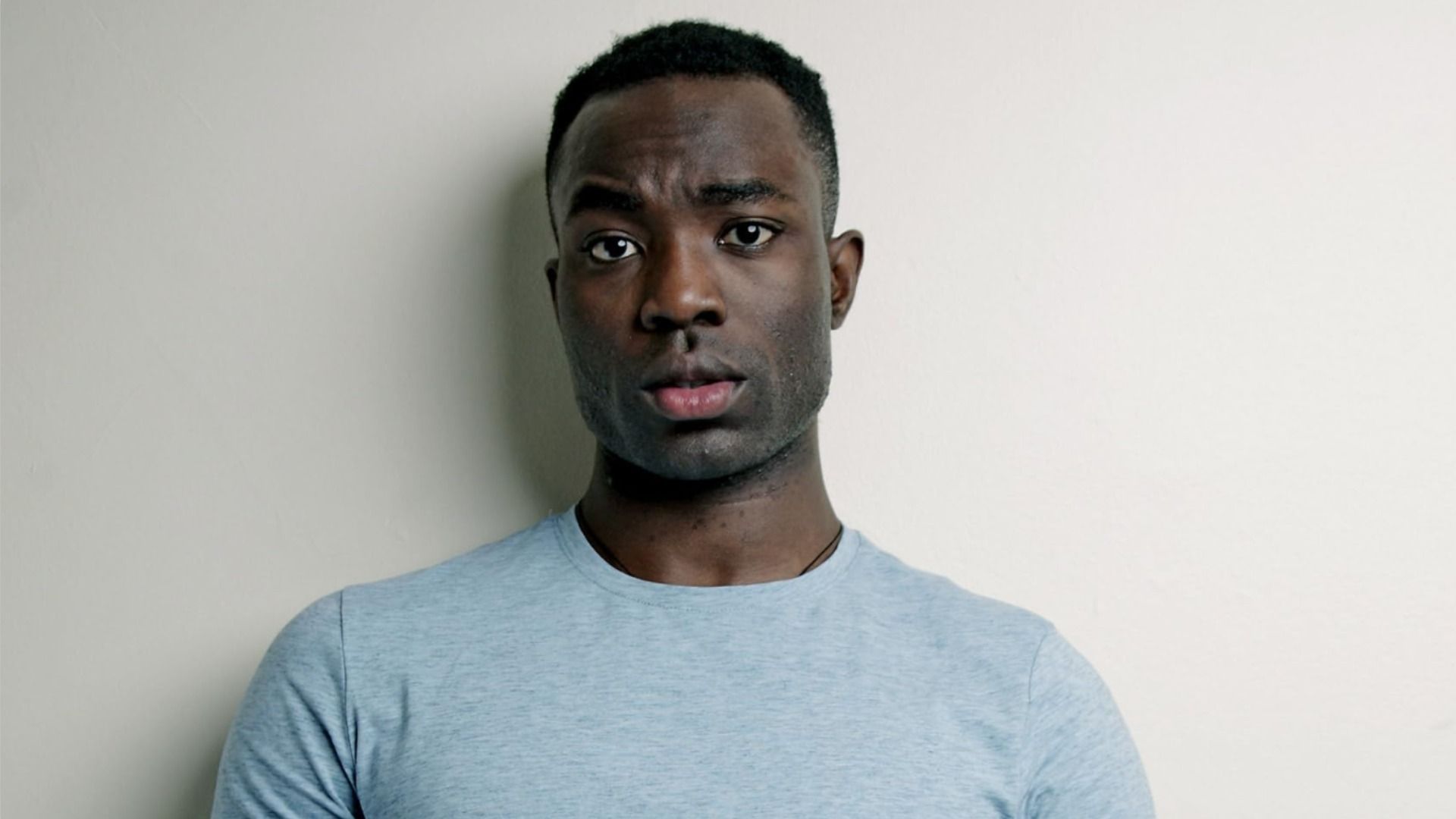 Actorul Paapa Essiedu stă în haine albastre și privește la cameră, ridicând o sprânceană