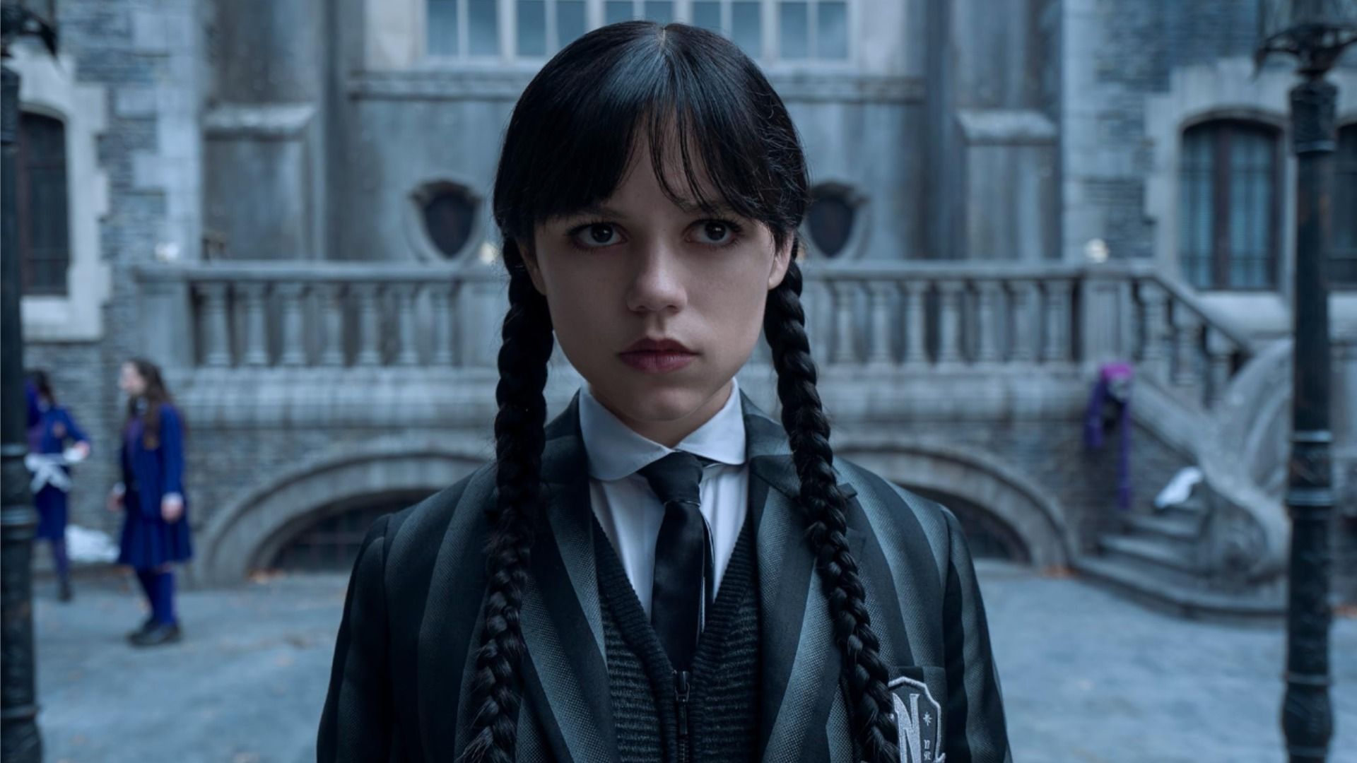 Actrița Jenna Ortega în uniformă școlară într-o scenă din serialul 'Wednesday', privind în lateral fără emoție