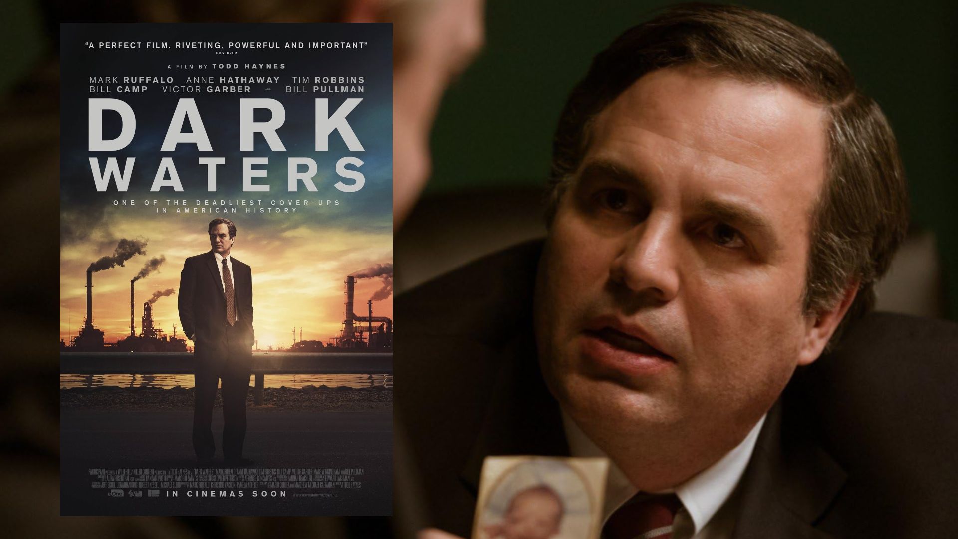 Actorul Mark Ruffalo într-o jachetă neagră arată o fotografie și se uită într-o parte