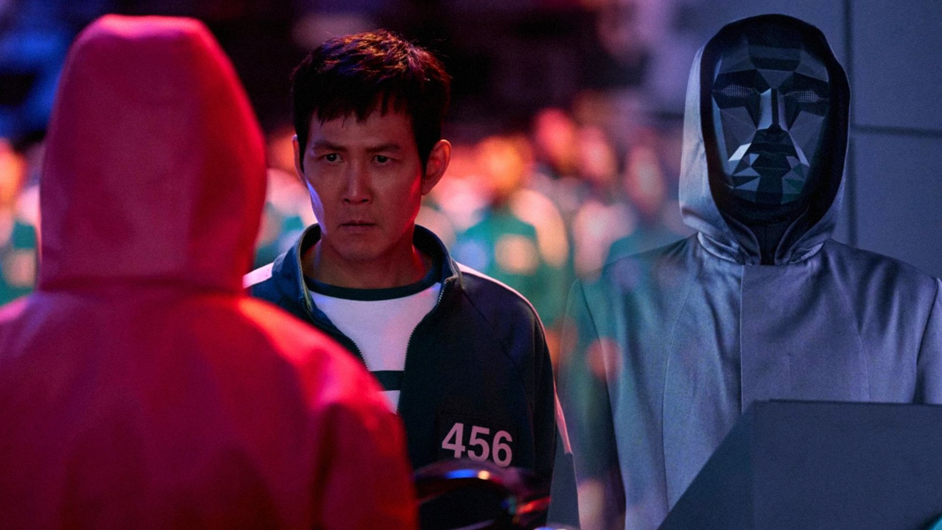 O persoană cu mască neagră și actorul Lee Jung-jae într-un costum verde privind într-o parte