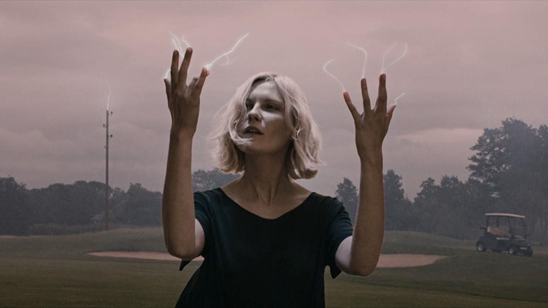 Actrița Kirsten Dunst se uită la degetele ei din care ies mici fulgere