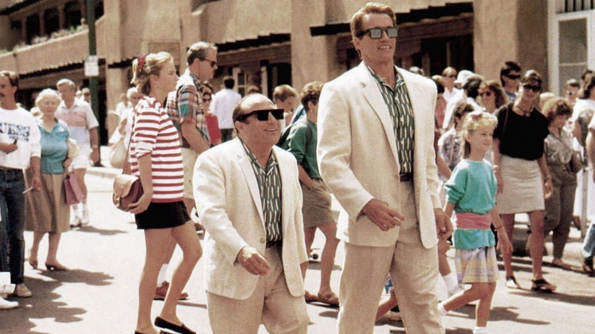 Danny DeVito și Arnold Schwarzenegger în costume albe mergând unul lângă altul