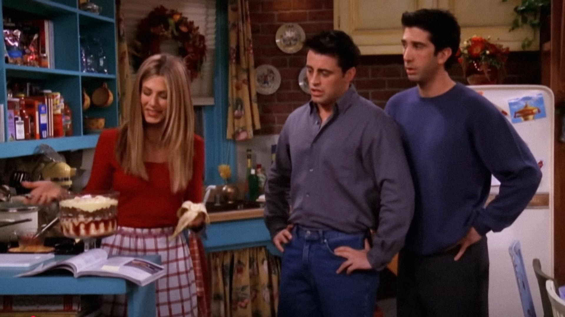 Actorii Jennifer Aniston, David Schwimmer și Matt LeBlanc uitându-se la o tavă transparentă cu caserola