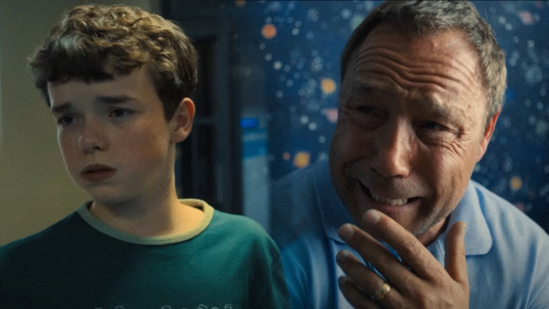 Owen Cooper în haine verzi se uită în lateral și actorul Stephen Graham plânge într-o cameră albastră