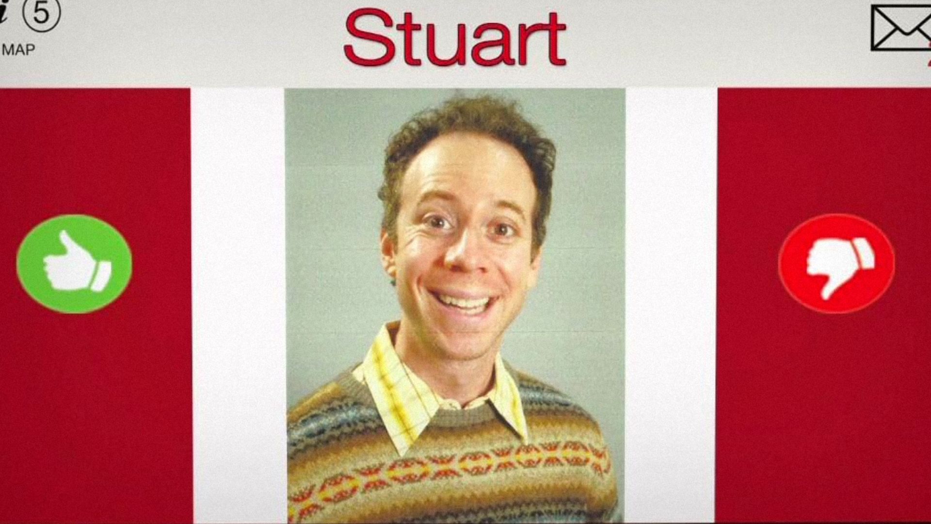 Actorul Kevin Sussman într-un pulover maro zâmbește pe un fundal cu numele "Stuart"