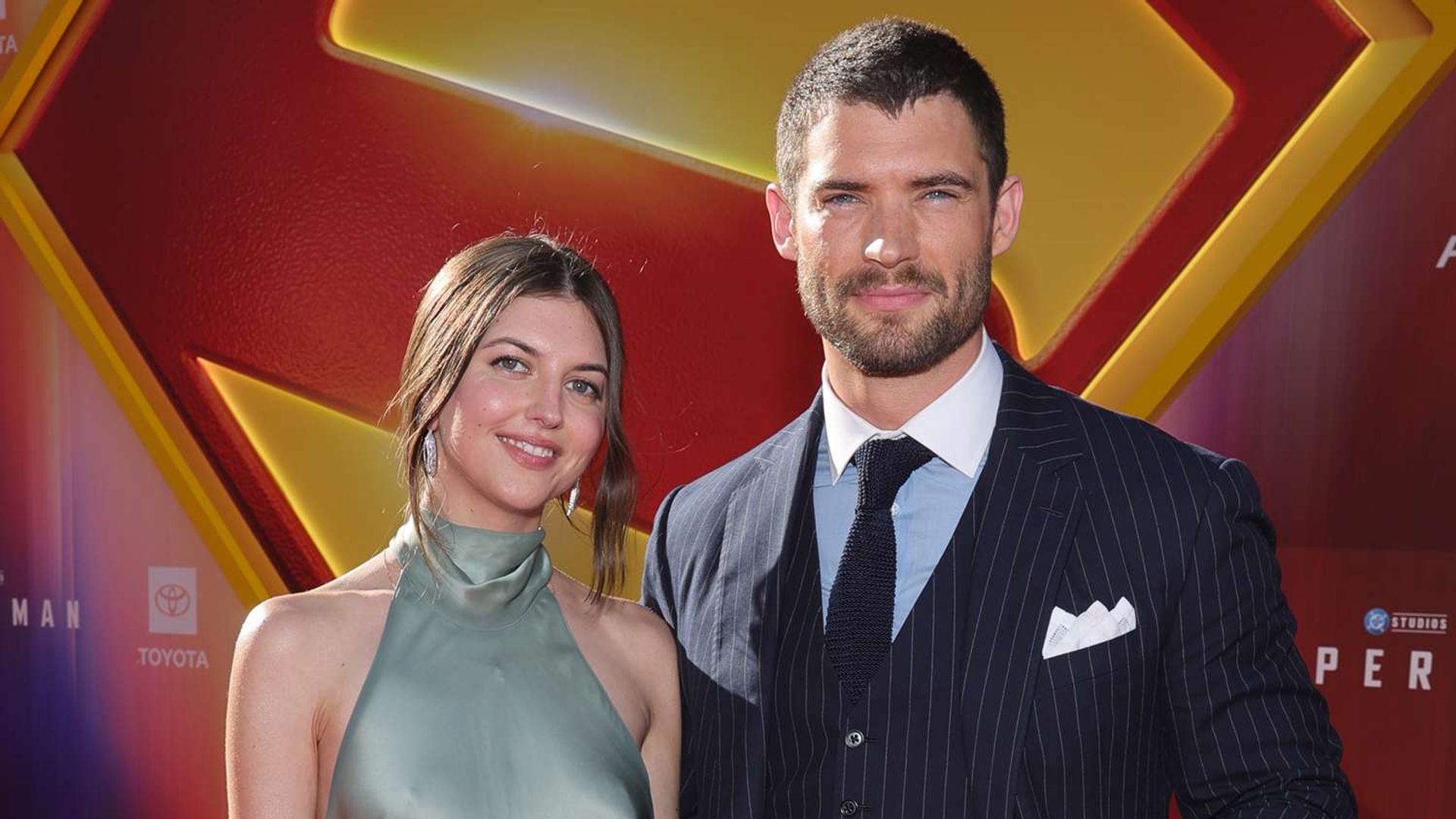 David Corenswet și Julia Warner pozează pe fundalul foto