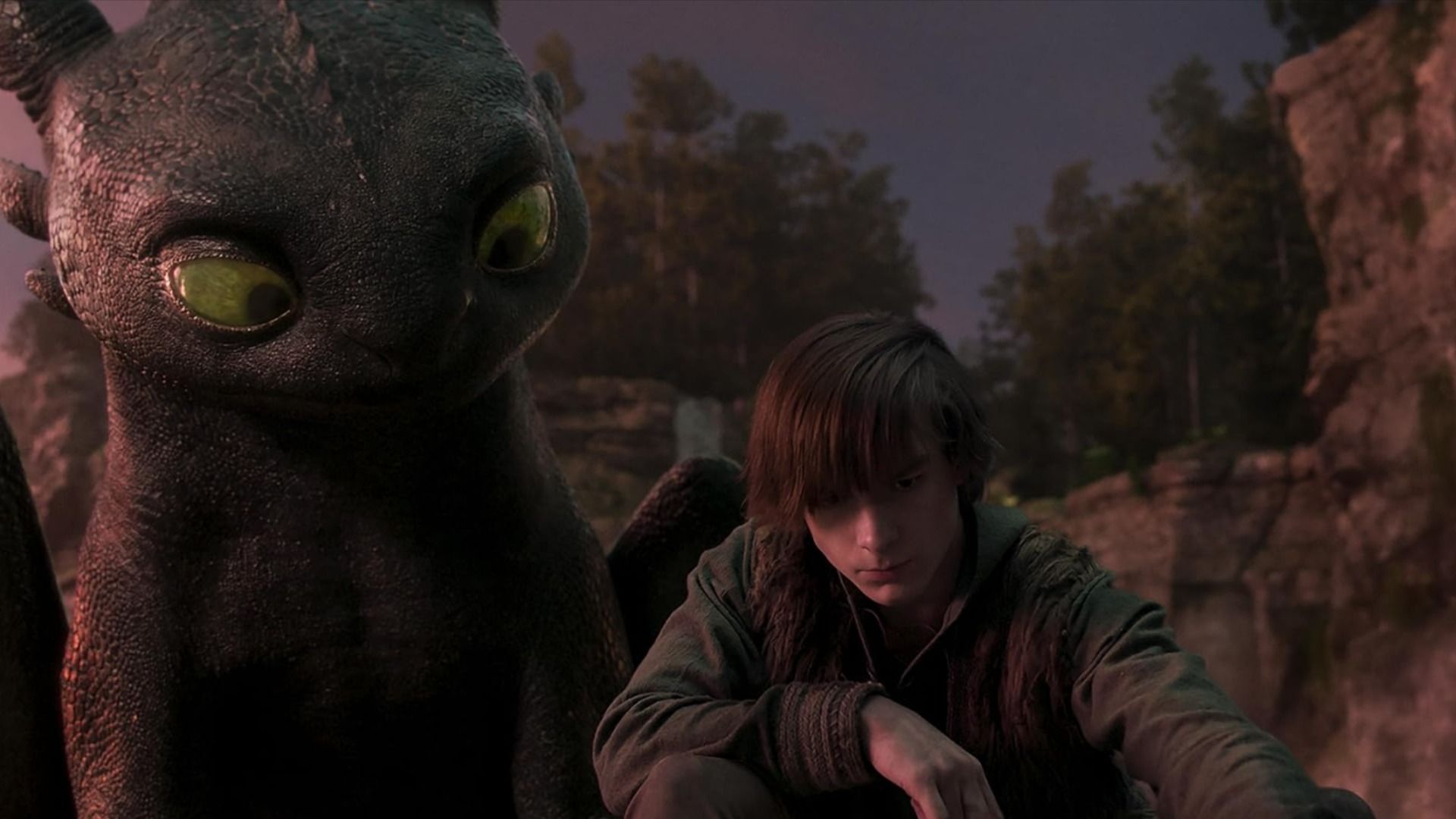 Un băiat în haine gri stă lângă un dragon negru cu ochi verzi