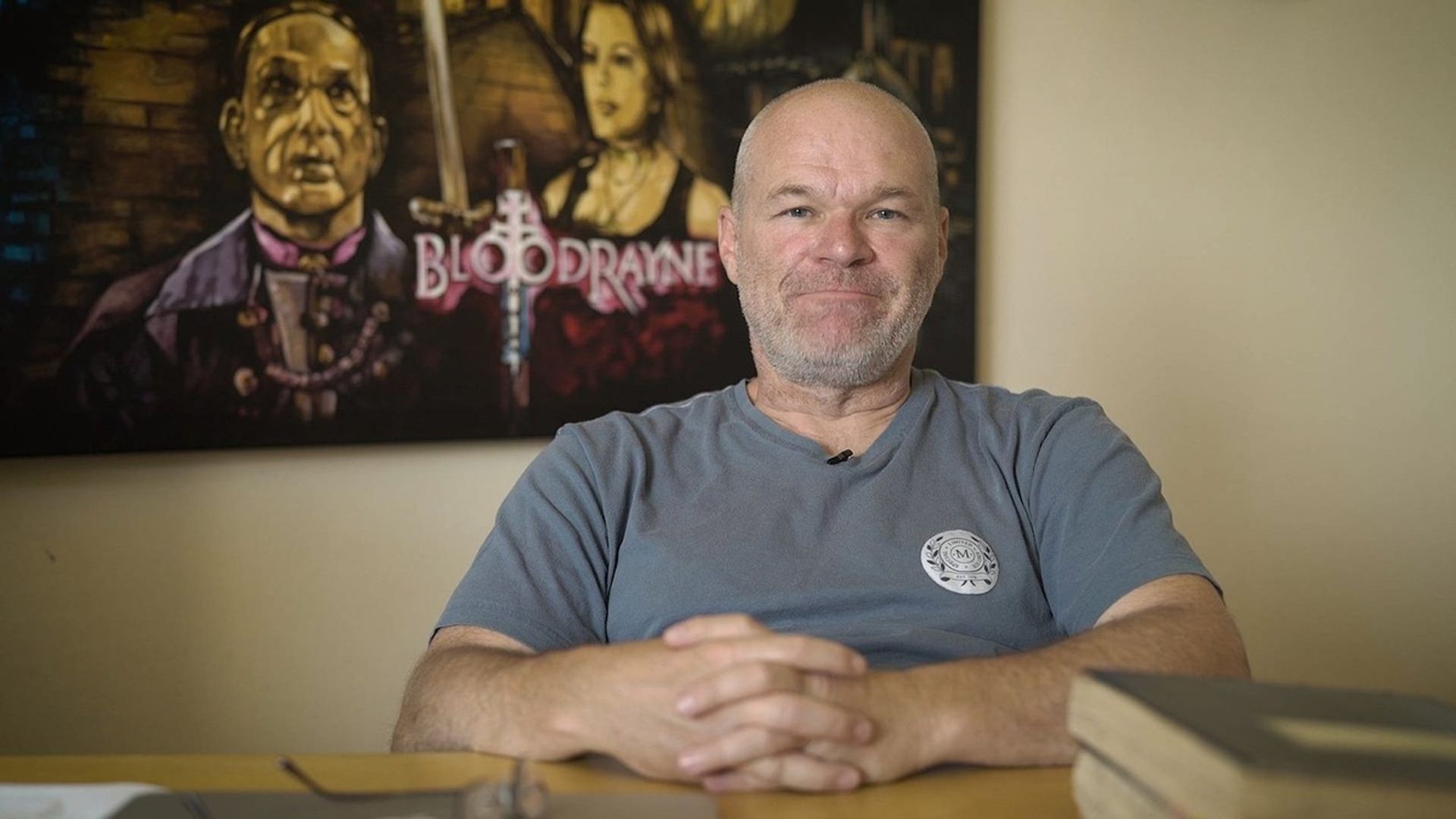 Regizorul Uwe Boll pe fundalul posterului filmului BloodRayne