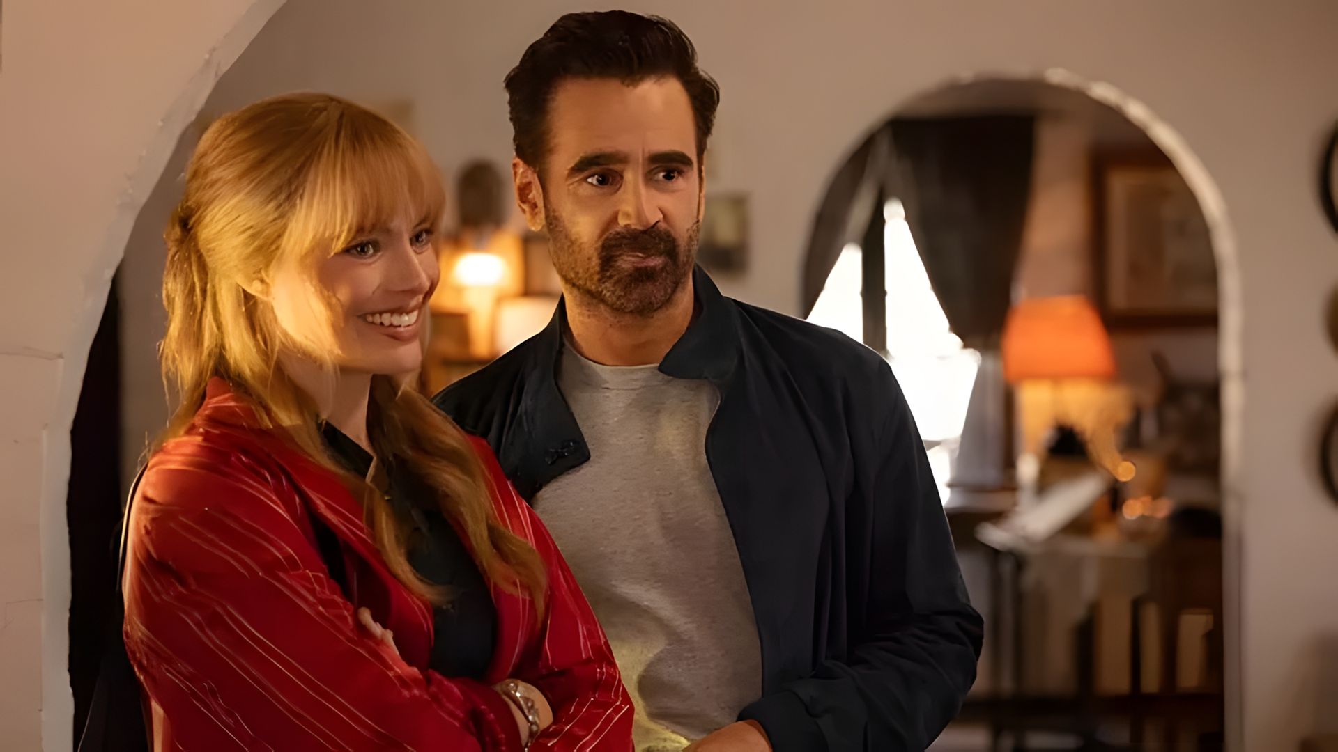 Margot Robbie și Colin Farrell stând unul lângă celălalt într-o cameră confortabilă cu iluminat cald și moale