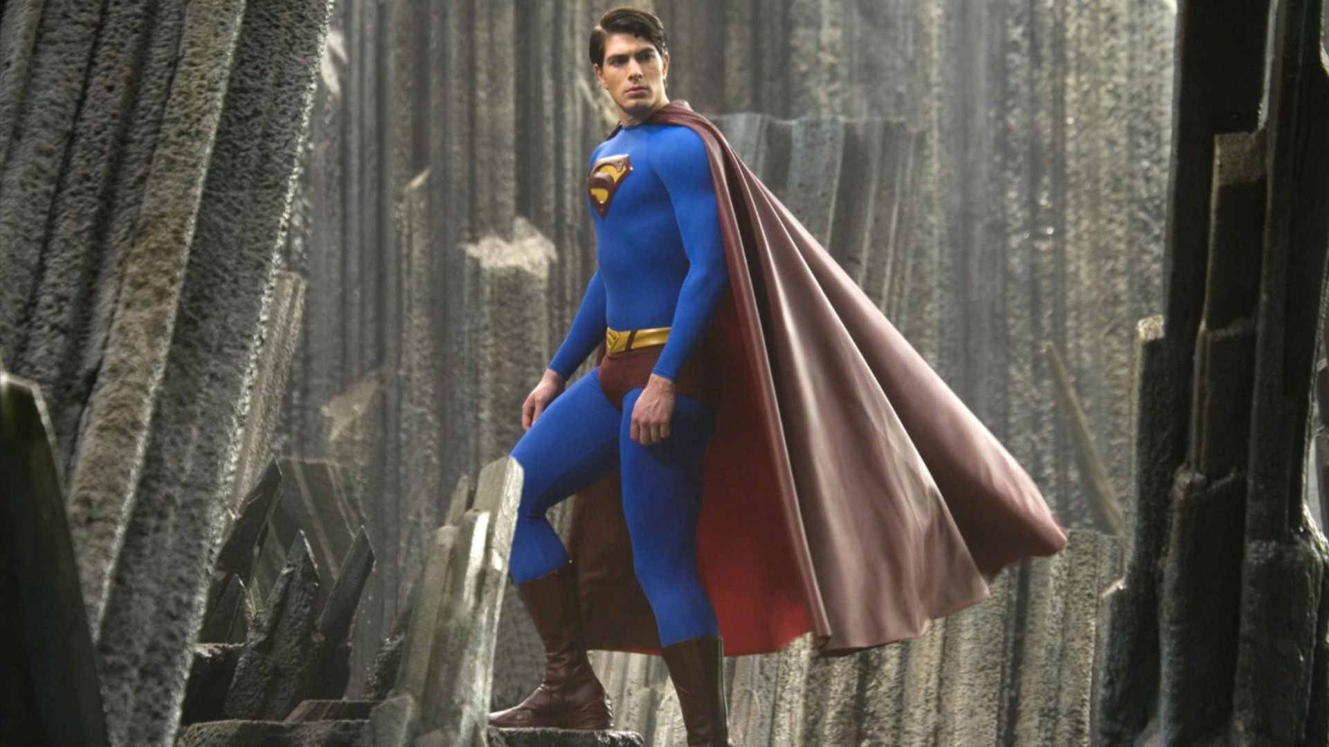Actorul Brandon Routh într-un costum de supererou albastru și roșu cu litera S pe piept urcă pe scări