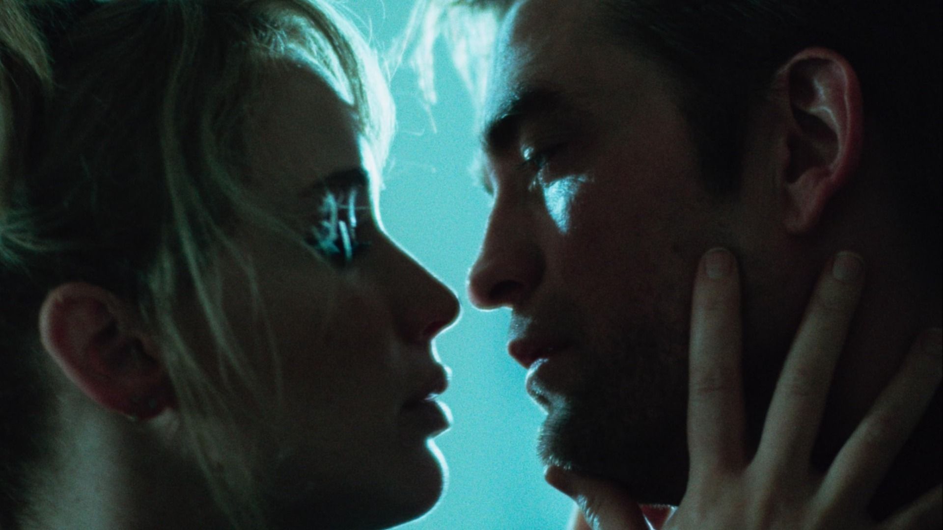 Actorii Jennifer Lawrence și Robert Pattinson se privesc în ochi pe un fundal albastru