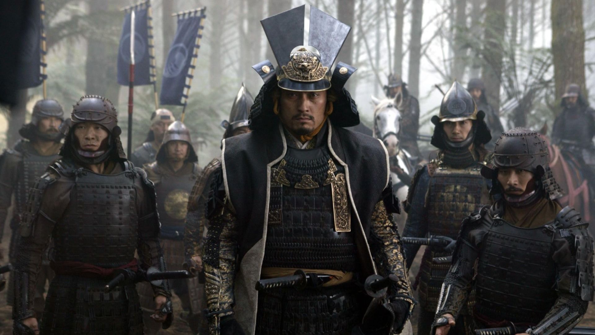 Actorul Ken Watanabe în armură întunecată de samurai stă înconjurat de alți samurai