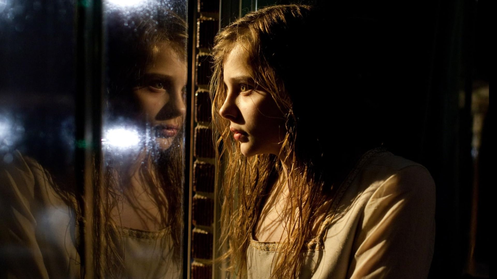 Actrița Chloë Grace Moretz se uită la reflecția ei în fereastră