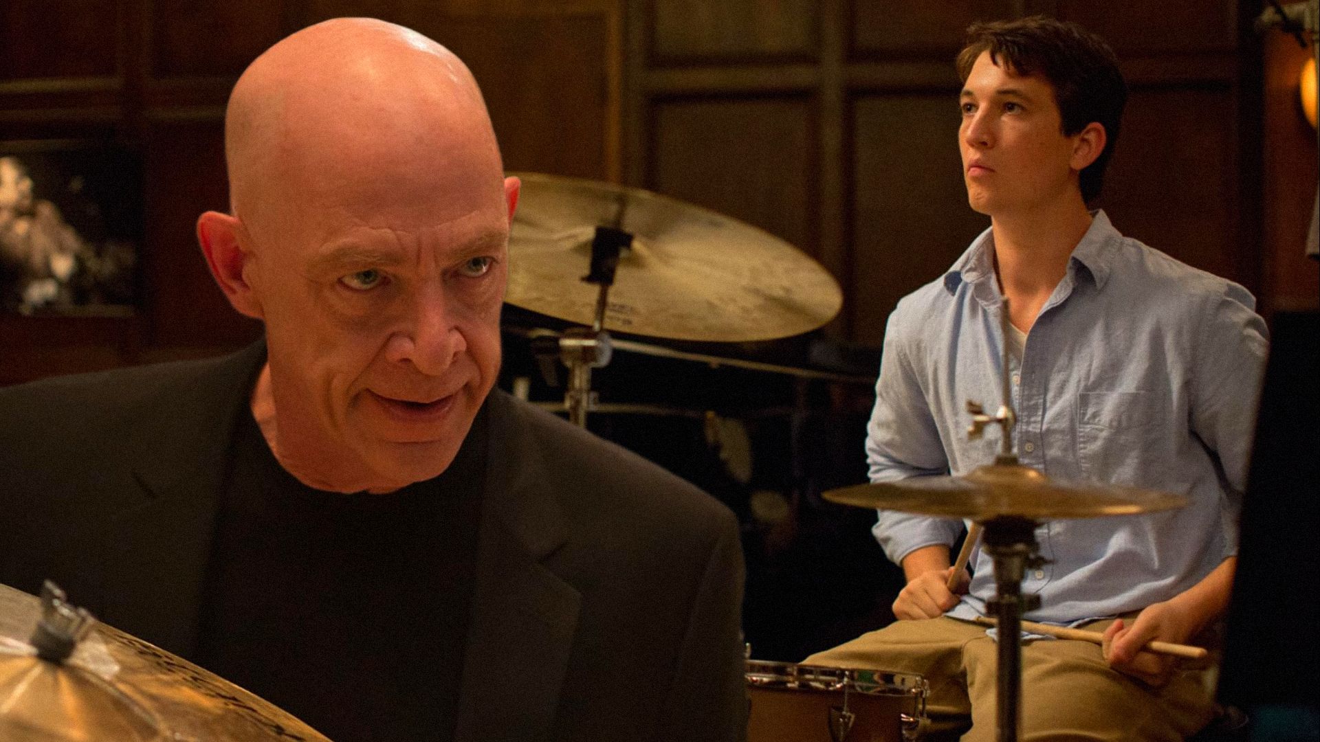 Actorul Miles Teller cântă la tobe în timp ce actorul J.K. Simmons îl privește amenințător