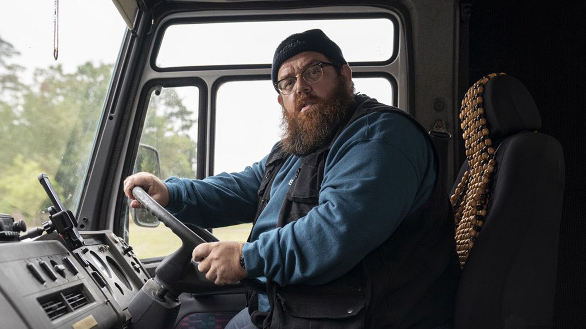 Nick Frost purtând ochelari și o pălărie stă la volanul unei camionete, privind spre cameră