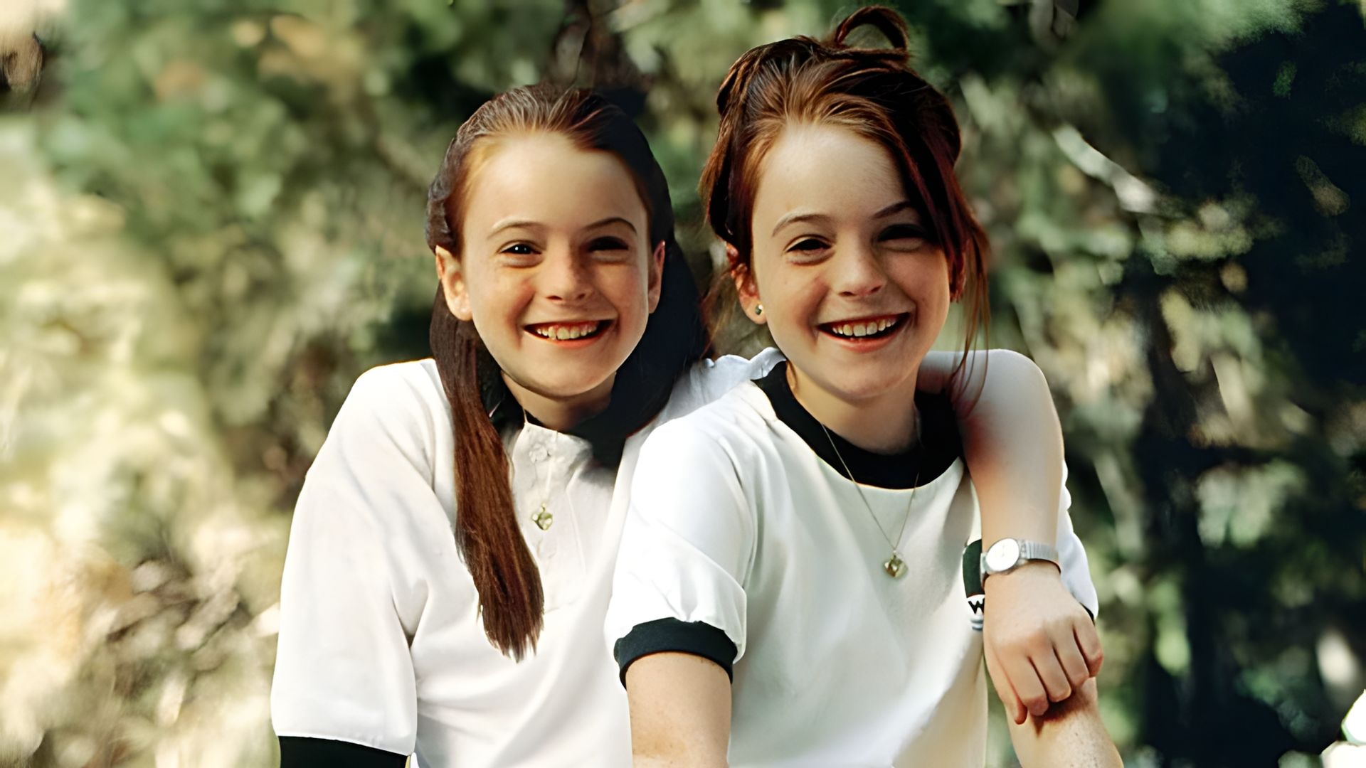 Lindsay Lohan în rolul gemenelor, ambele purtând tricouri albe pe un fundal verde