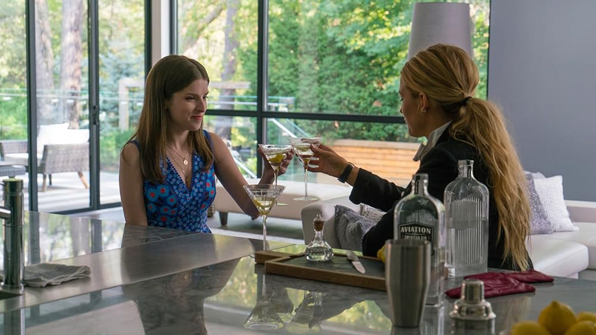 Anna Kendrick și Blake Lively ciocnind pahare de vin stând în bucătărie