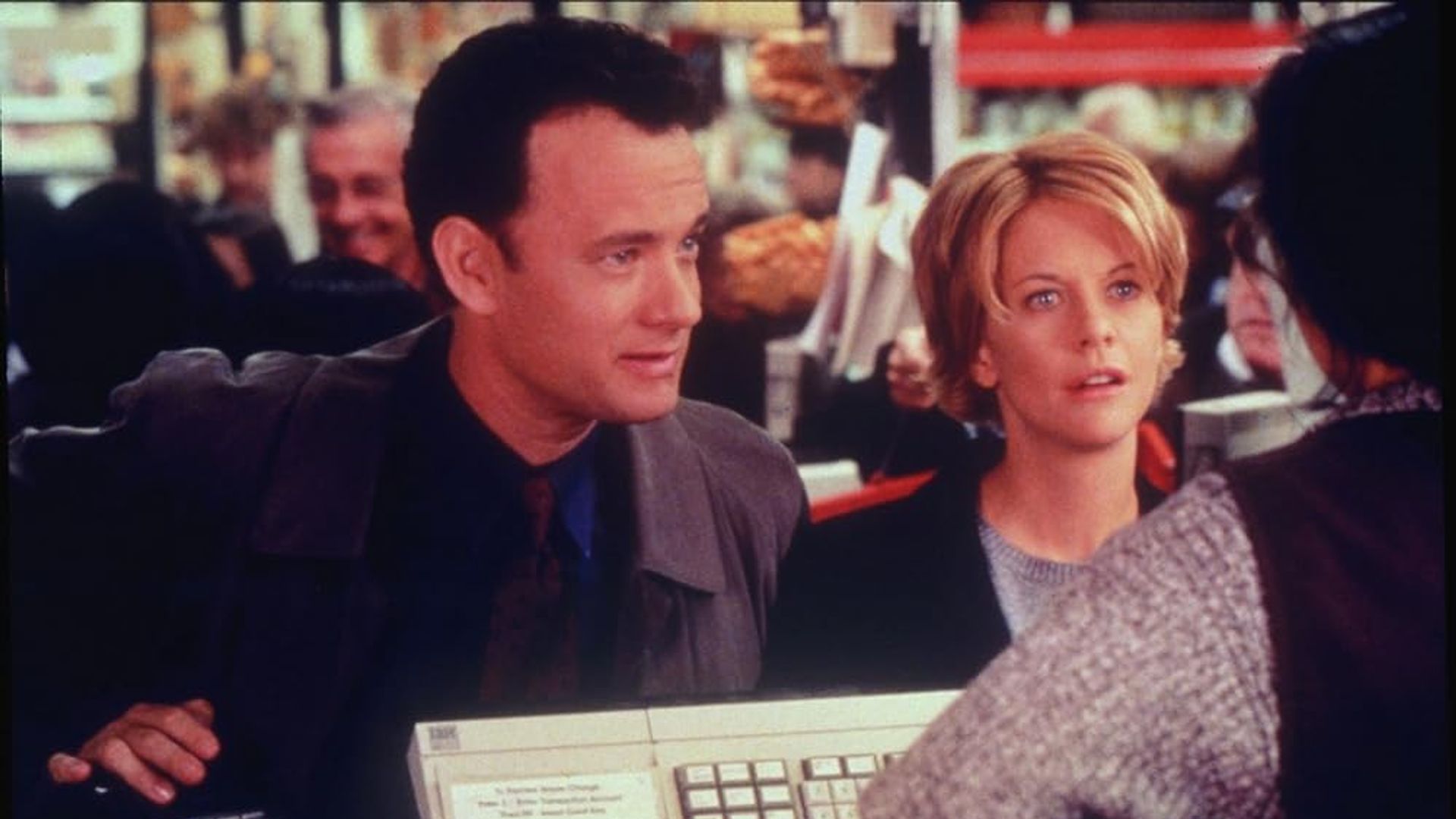 Tom Hanks și Meg Ryan stând la casa de marcat într-un magazin, vorbind cu casierul