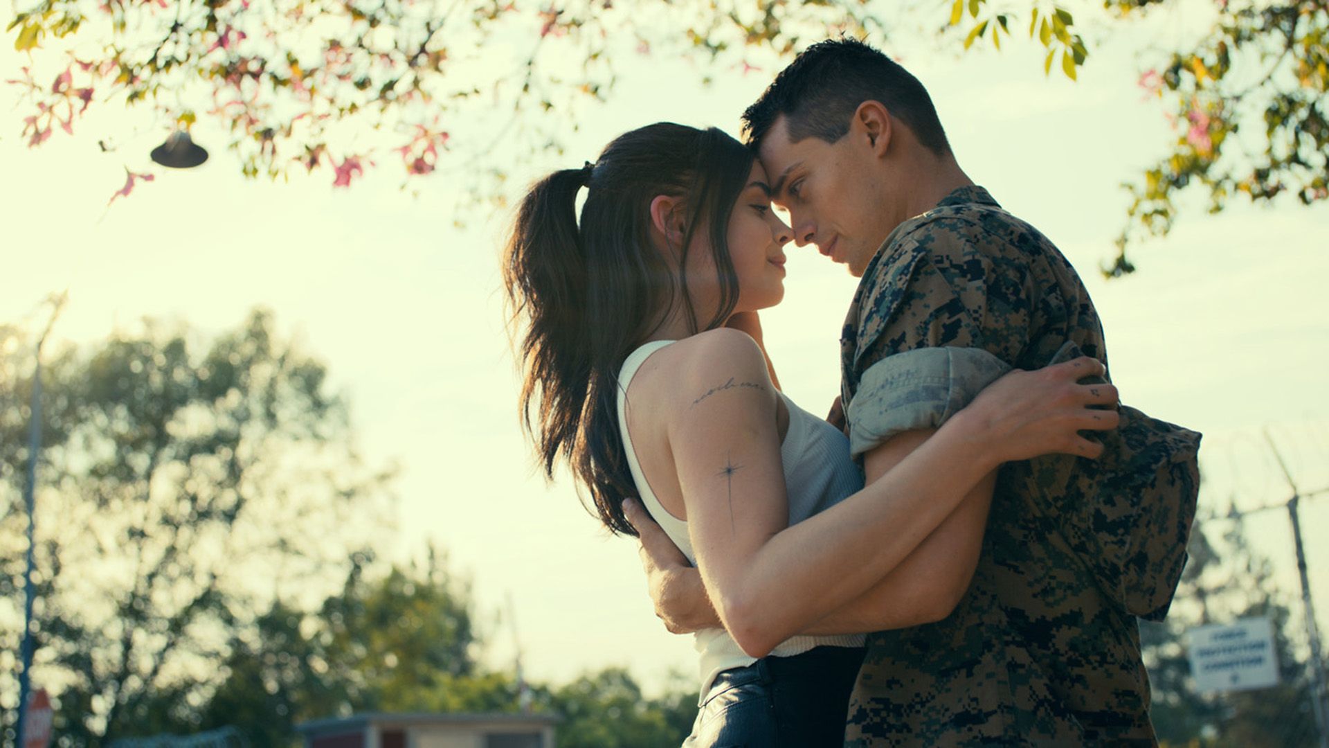 Sofia Carson și Nicholas Galitzine se îmbrățișează stând sub un copac