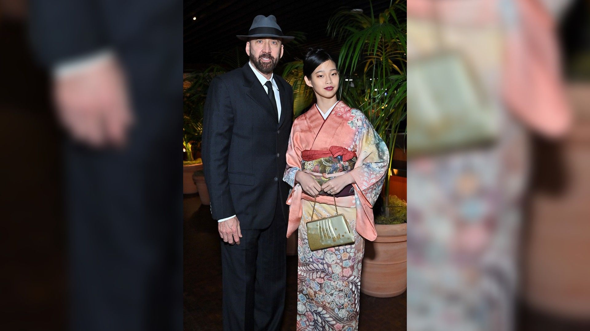 Nicolas Cage într-un costum negru și pălărie și Riko Shibata într-un kimono roz cu model
