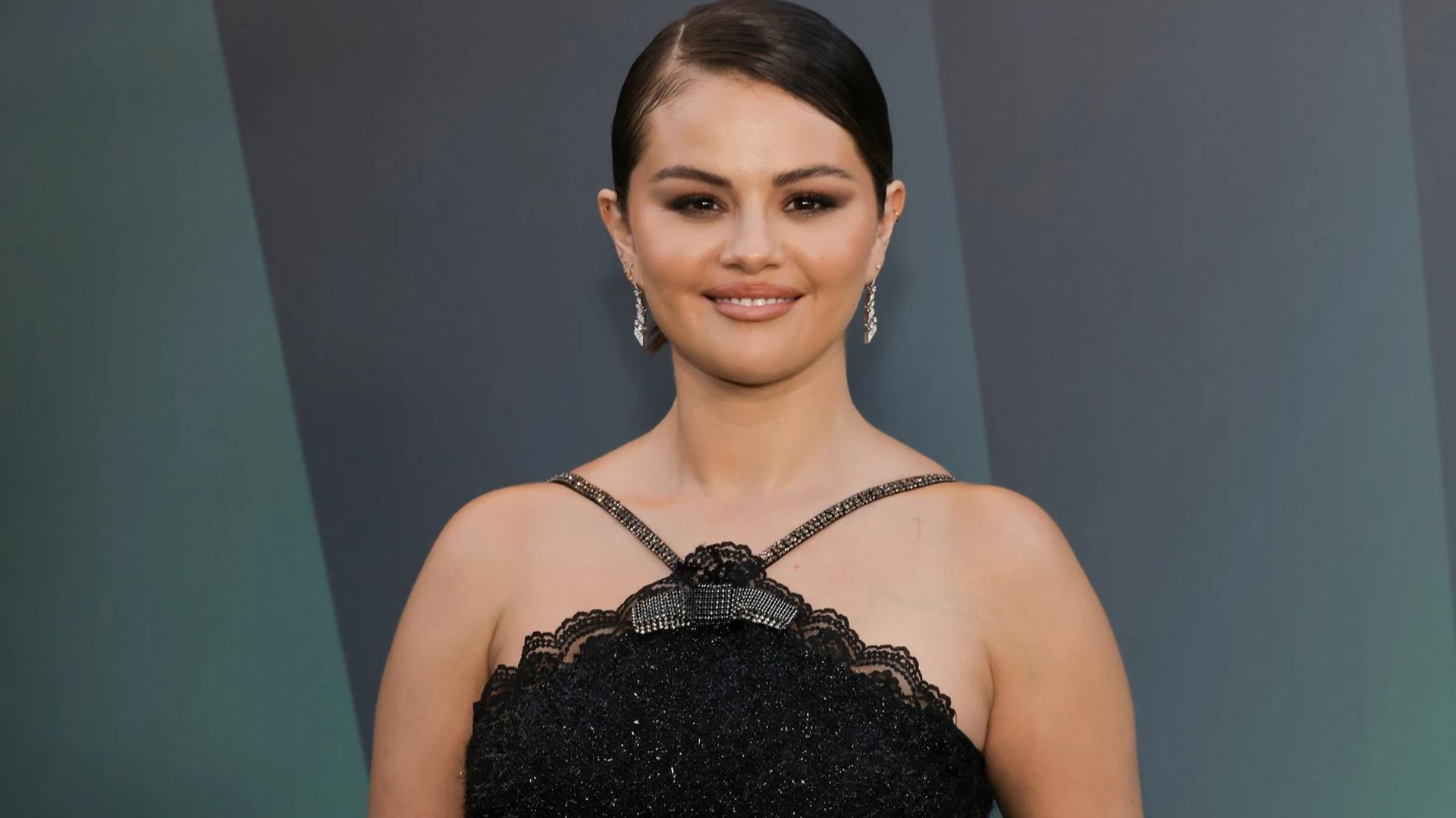 Selena Gomez într-o rochie neagră pozează pentru camere cu un zâmbet blând