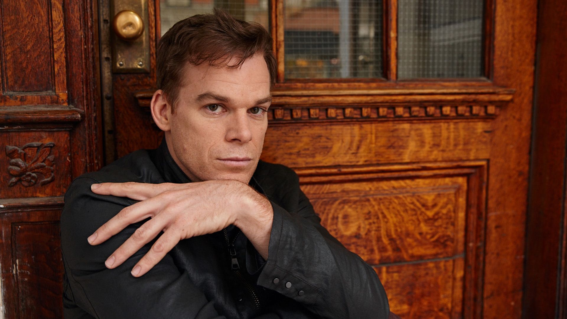 Actorul Michael C. Hall pozează în fața unei uși de lemn