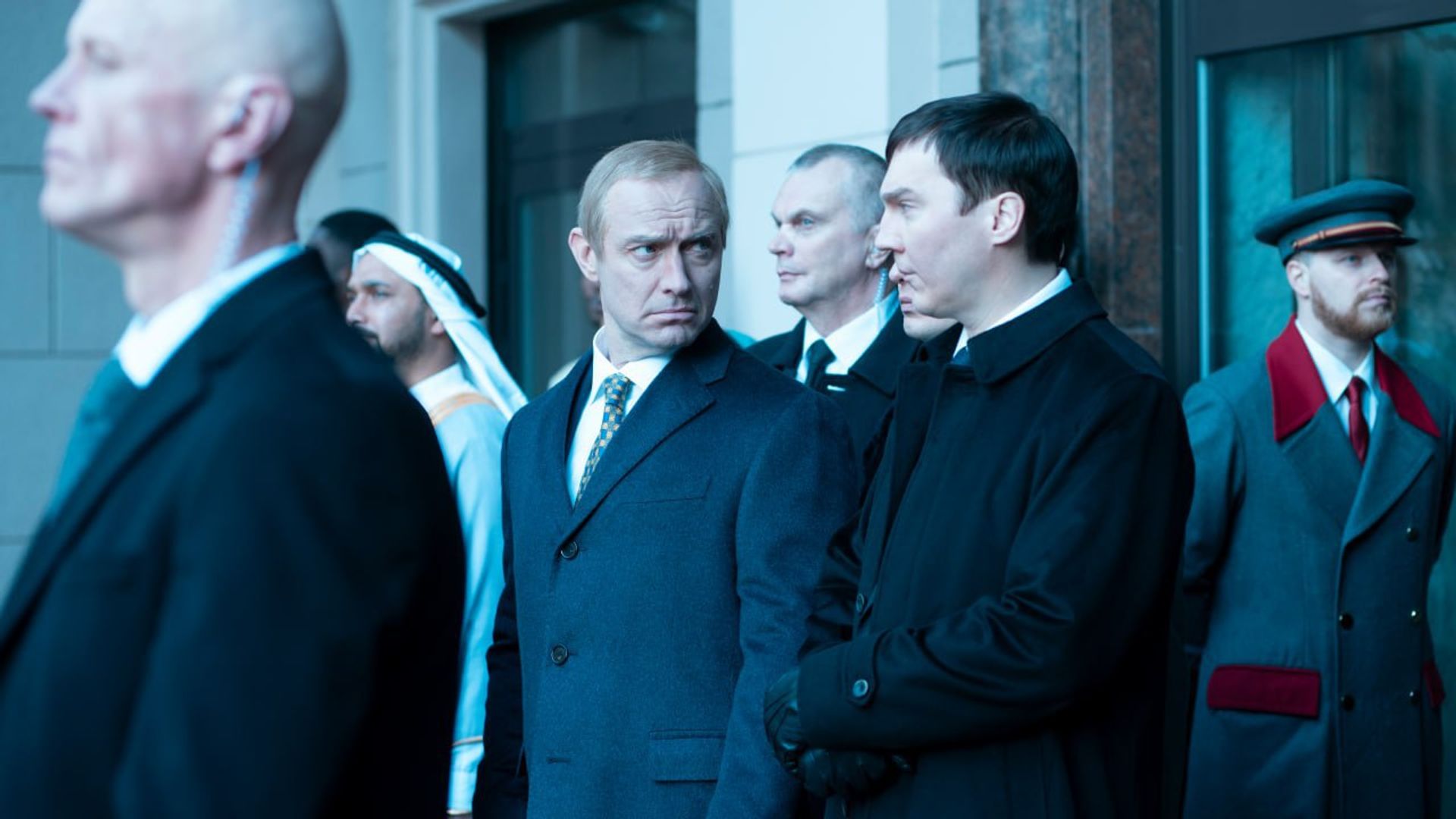 Jude Law și Paul Dano în costume, având o conversație serioasă