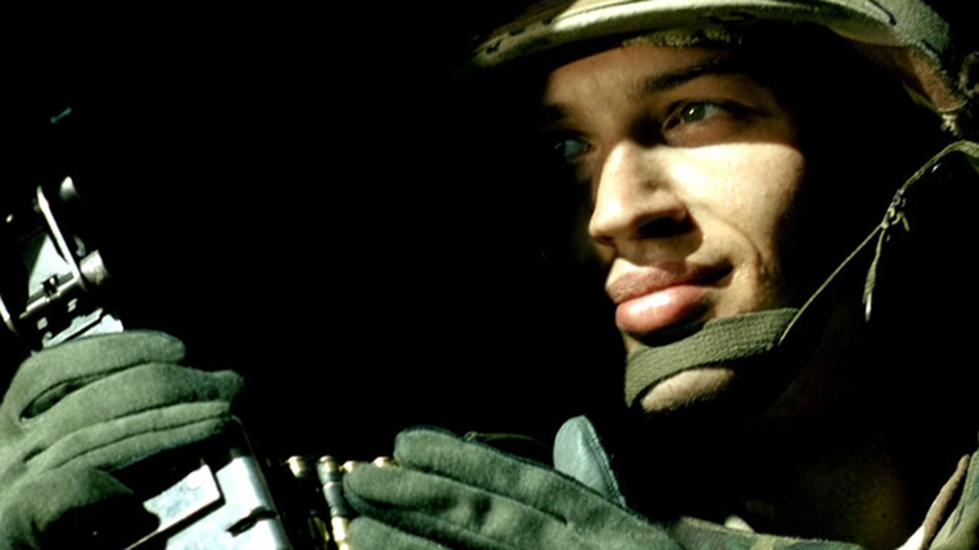 Tom Hardy în uniformă militară și cască, fața pe jumătate ascunsă în umbră