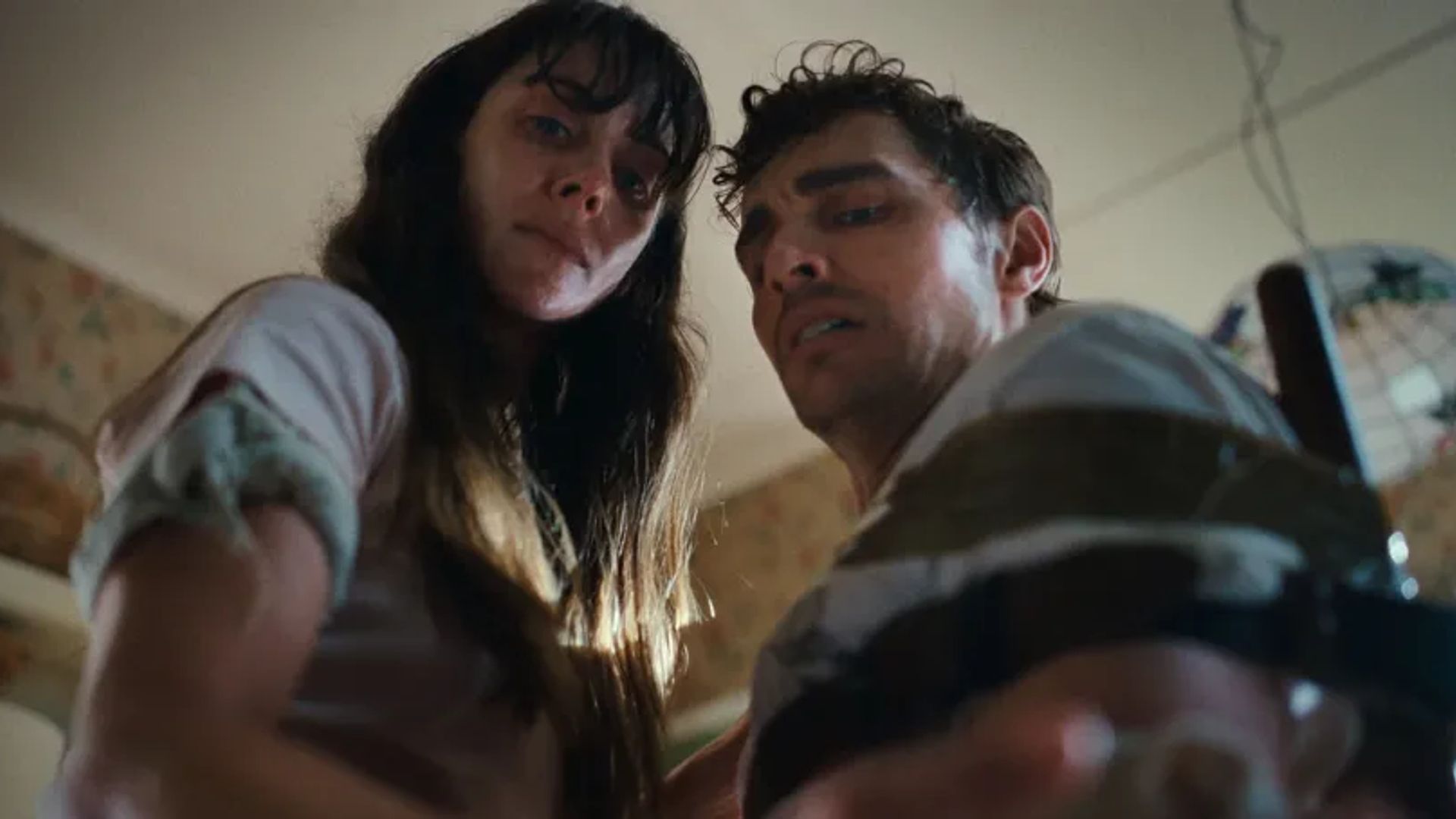 Alison Brie și Dave Franco se uită în cameră cu expresii îngrijorate, filmați dintr-un unghi jos