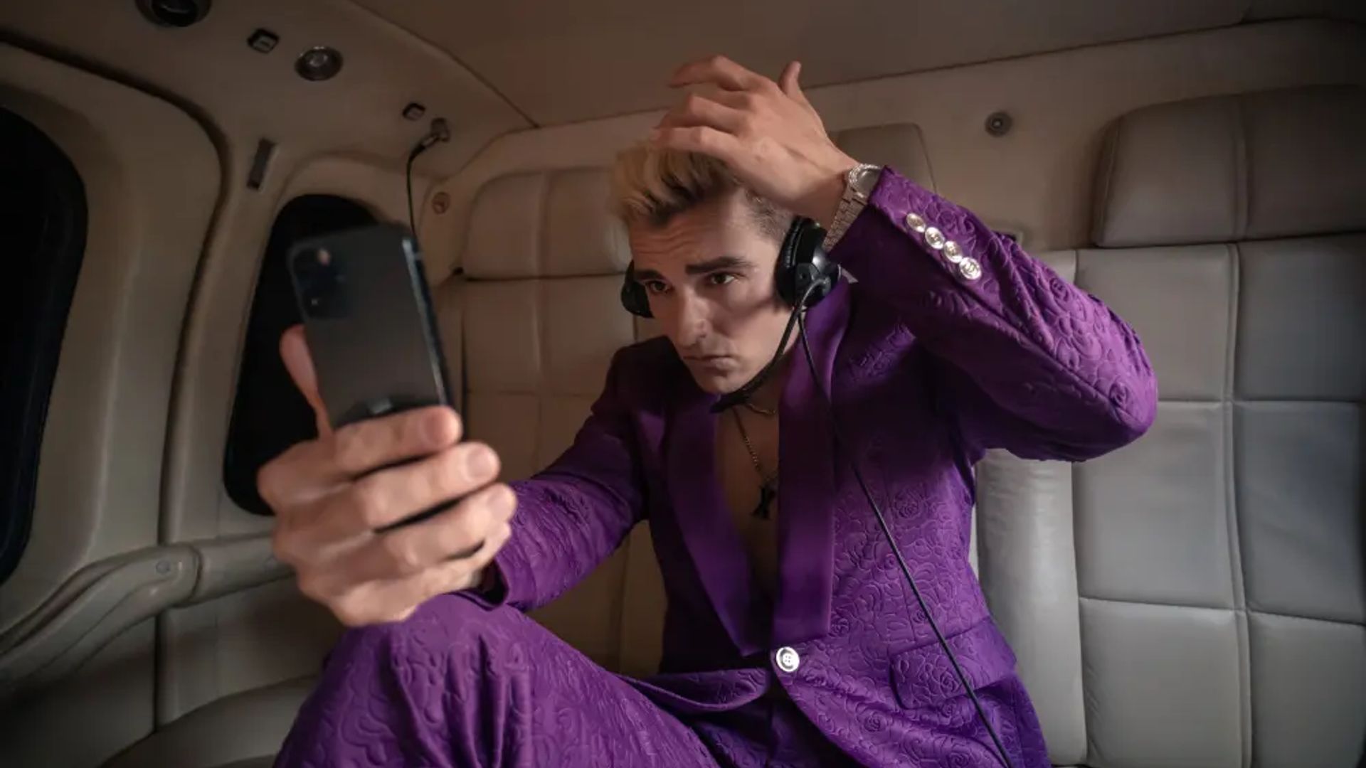 Dave Franco într-un costum mov uitându-se la telefon, scenă din serialul The Afterparty