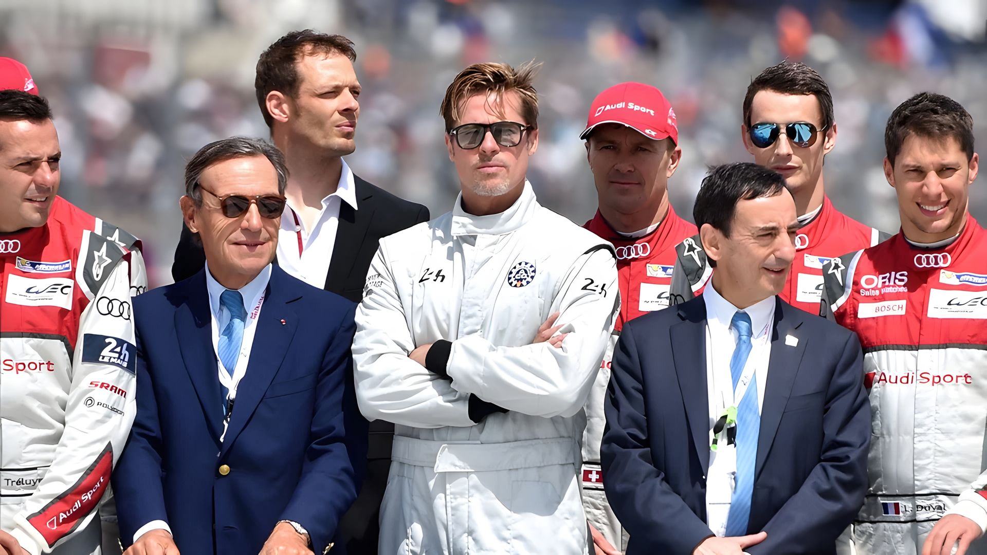 Brad Pitt în echipament de pilot de curse stă înconjurat de echipa sa