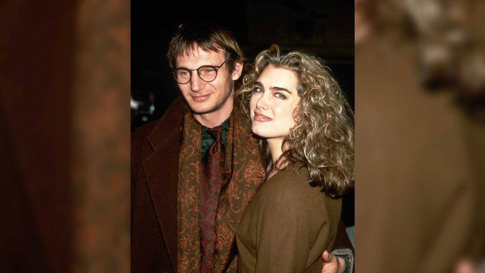 Liam Neeson și Brooke Shields în tinerețe, îmbrățișându-se și mergând înainte