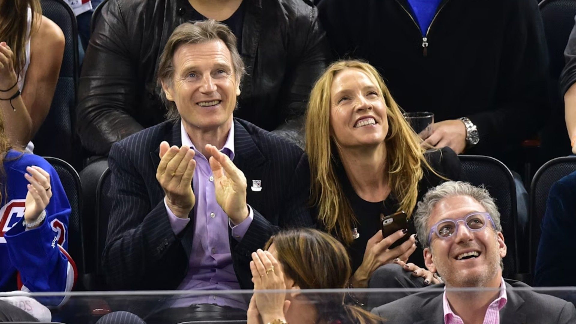 Liam Neeson și Freya St. Johnston stau în tribune în timpul unui meci sportiv și se bucură cu entuziasm