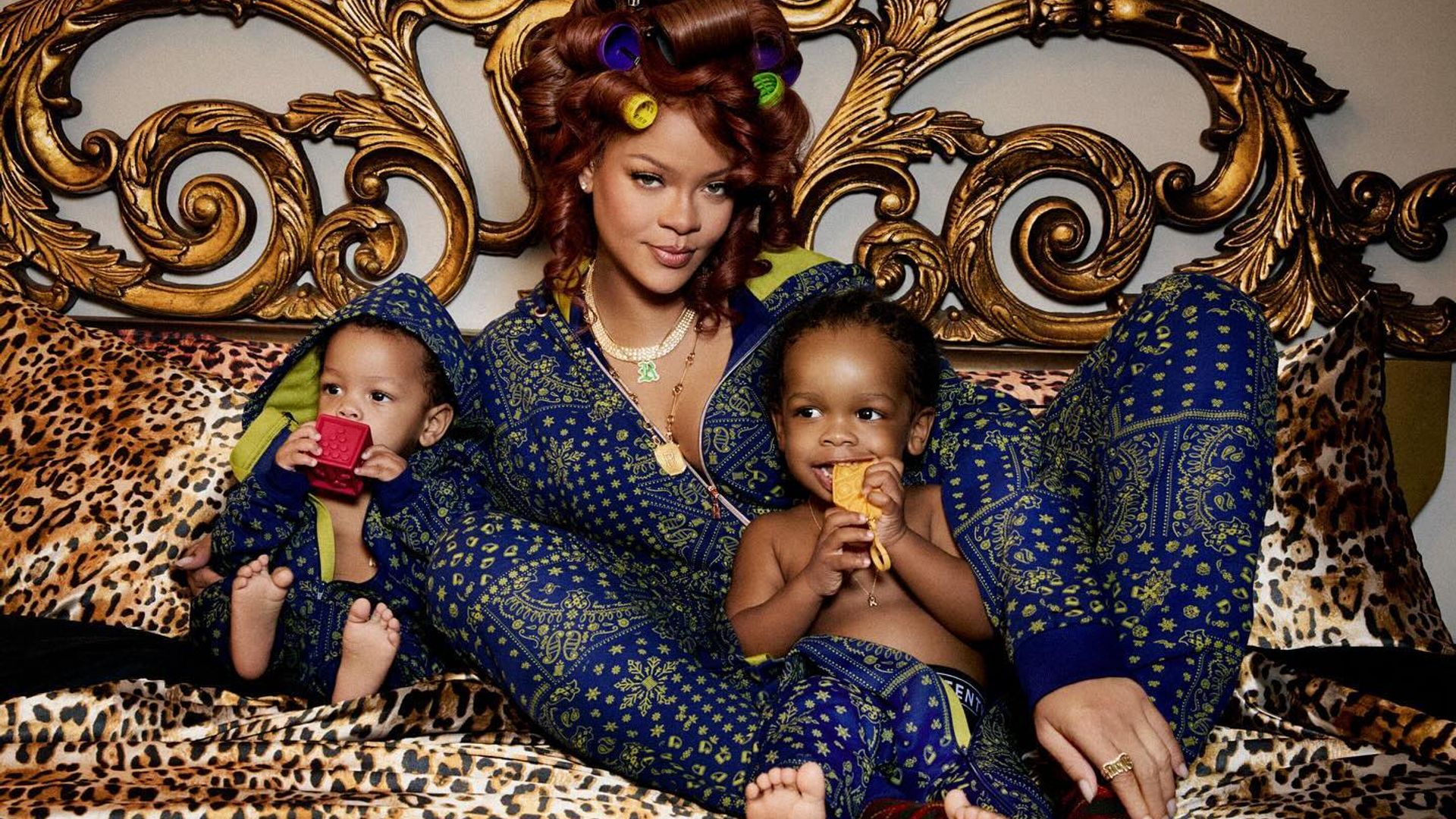 Rihanna în pijamale de mătase stând în pat îmbrățișându-și fiii, cadru din sesiunea foto