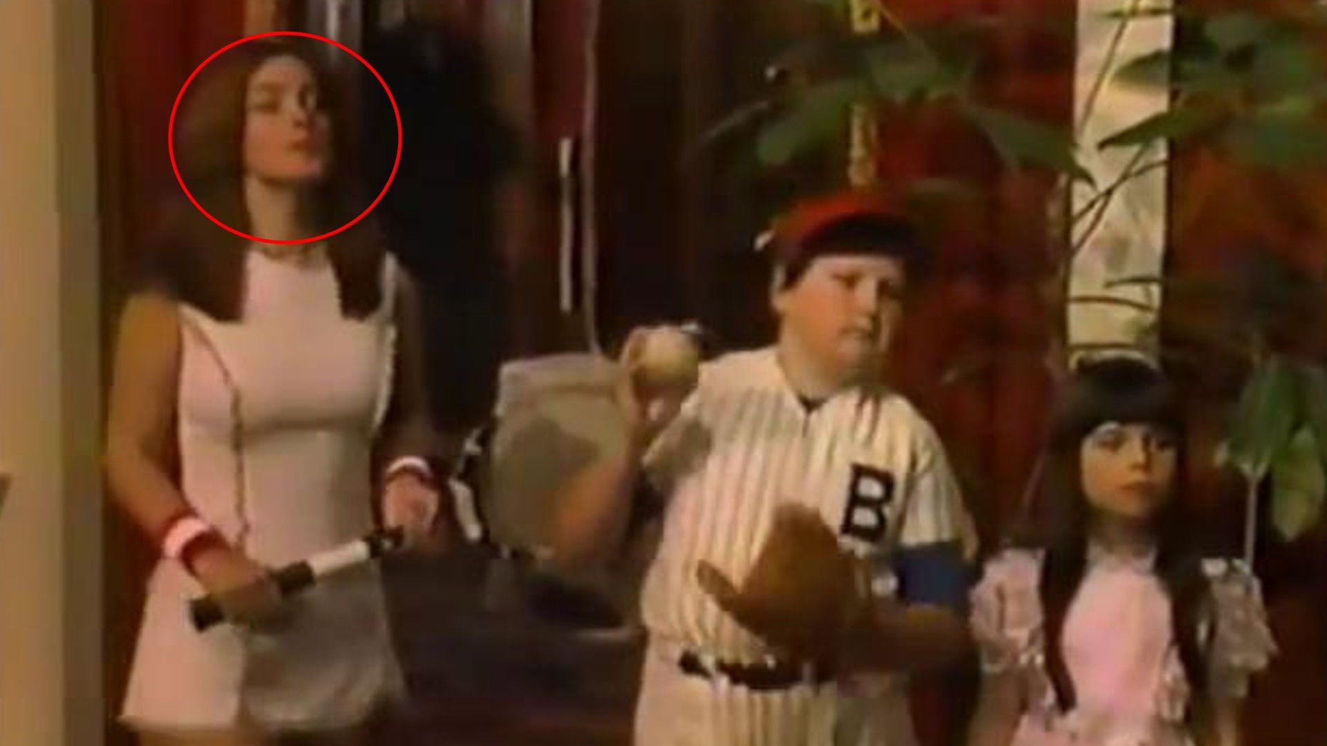 Femeie în ținută albă de tenis cu rachetă și doi copii în haine de baseball și roz în interior