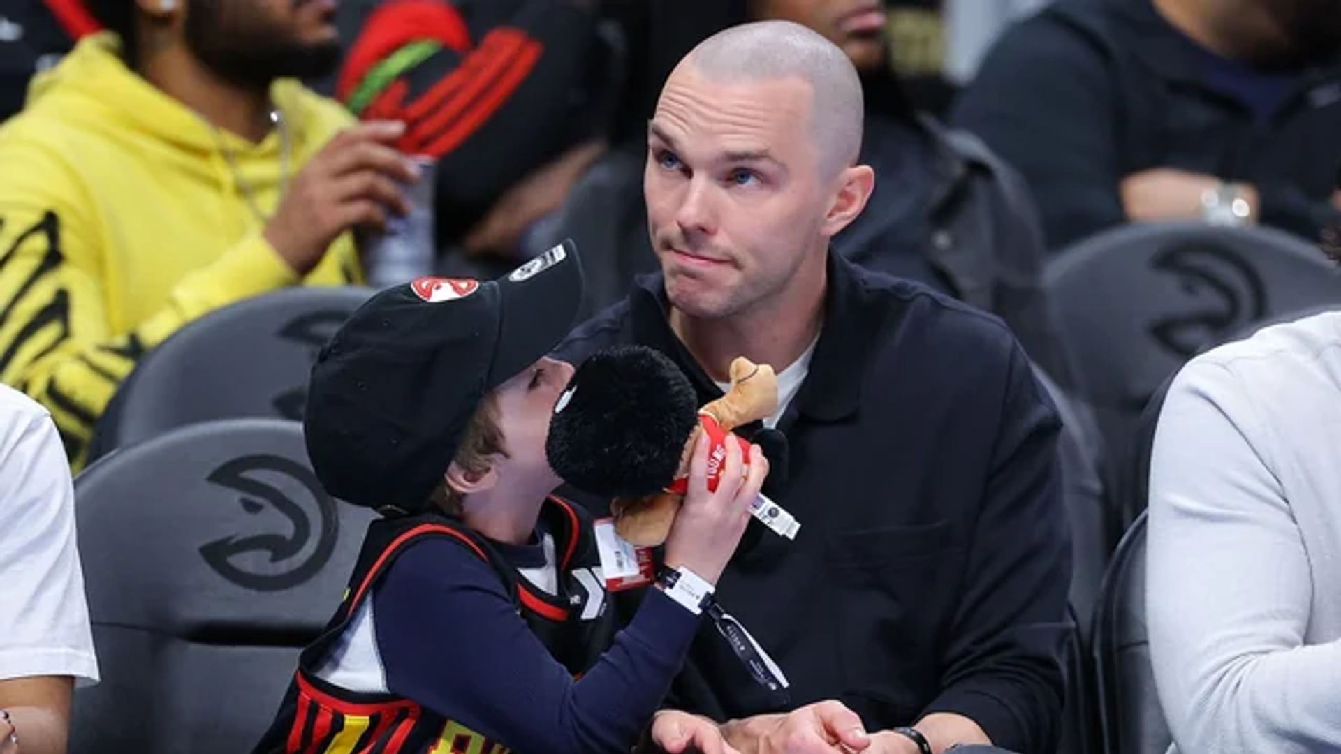 Nicholas Hoult stă în tribune la un meci de baschet lângă fiul său care ține o jucărie