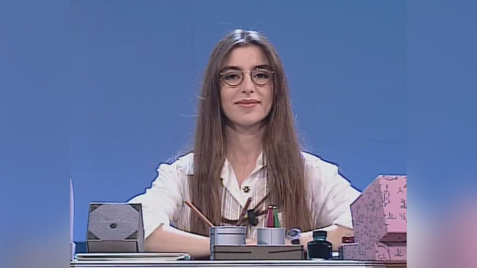 Tânăra Sabrina Impacciatore cu ochelari și bluză albă stă la birou