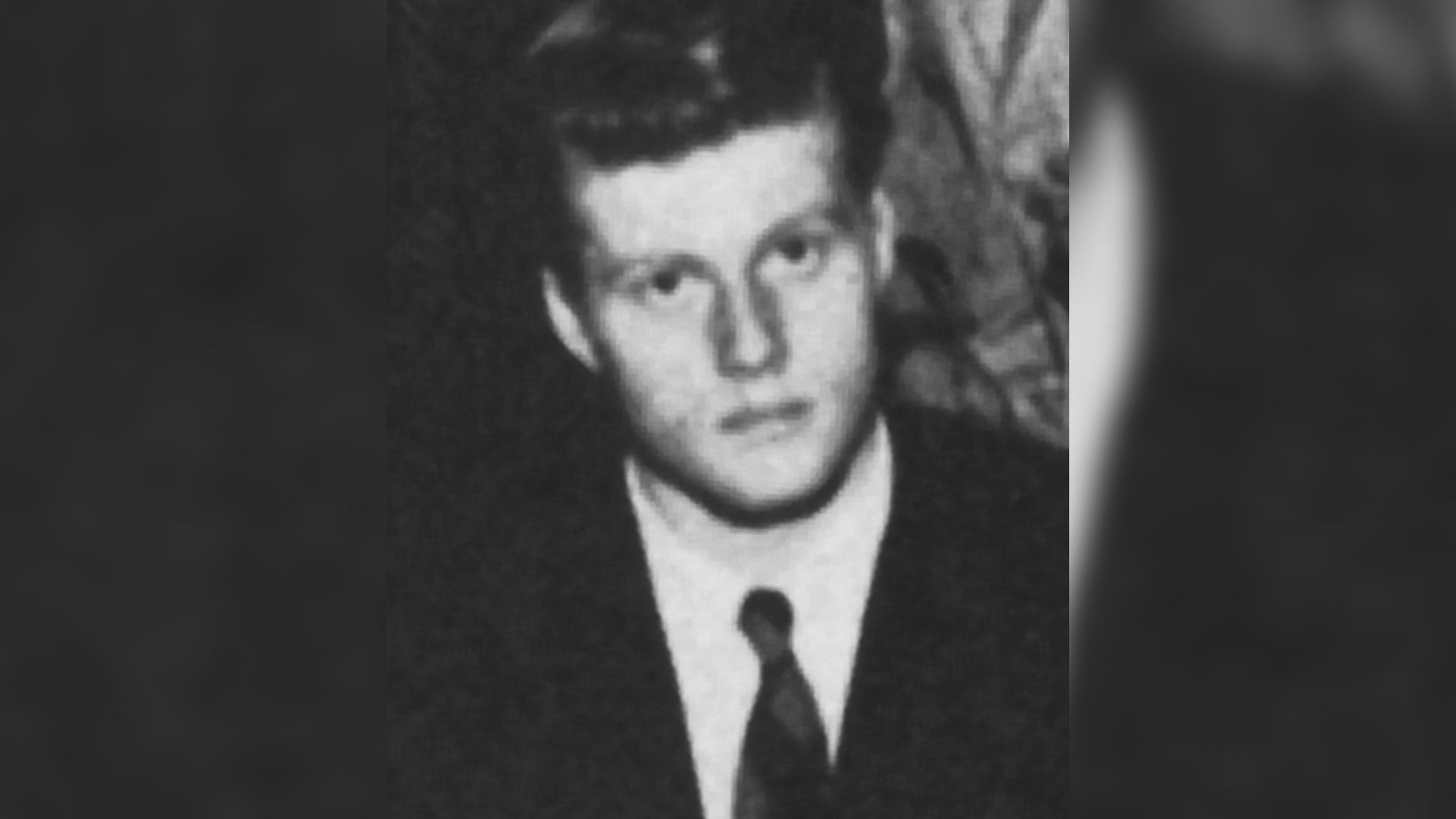 Un portret alb-negru al tânărului Robert Redford în costum și cravată, privind direct către cameră.